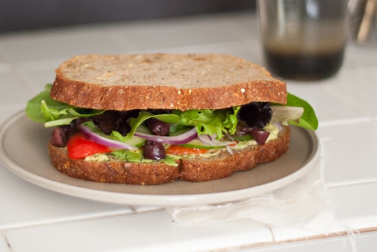 sandwich with avocado, pesto, roasted red bell pepper, olives and spring mix
