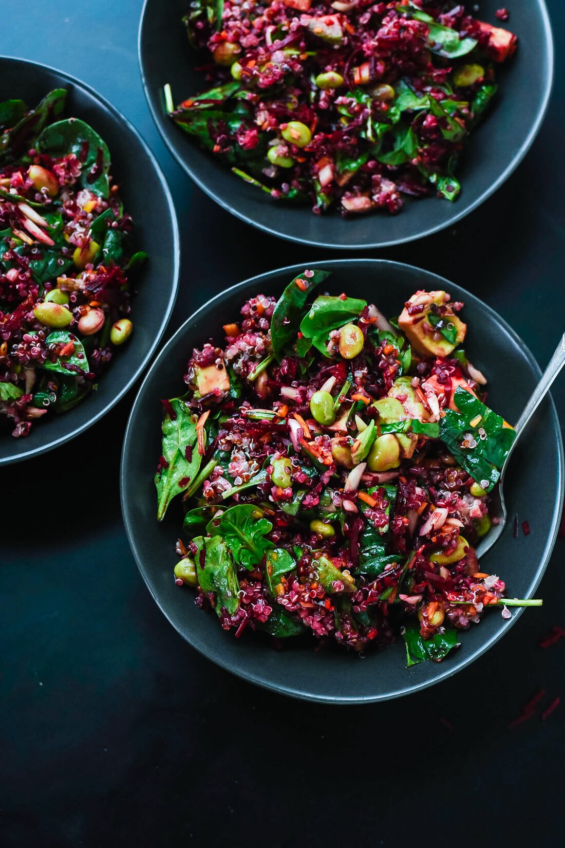 Salad of raw beets with carrots, quinoa and spinach in bowls