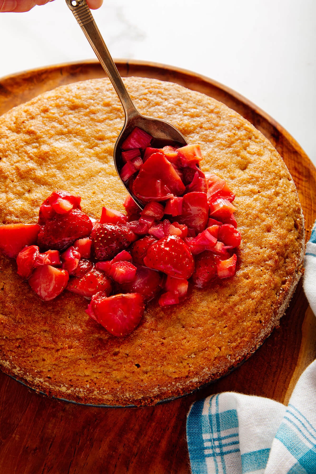 spooning strawberry rhubarb topping over cake