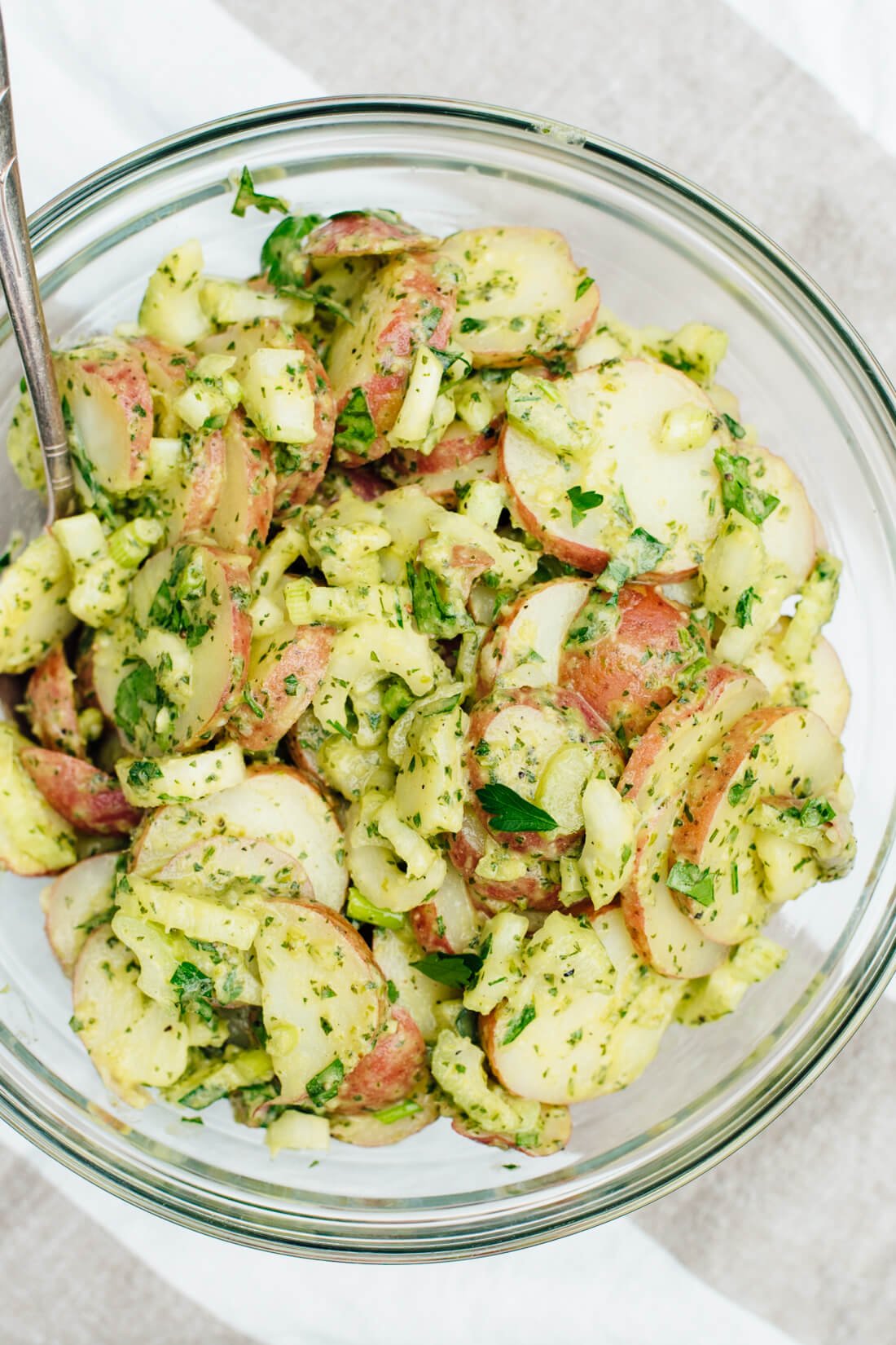 This simple, herbed red potato salad recipe will be a hit at your next potluck!  The light, creamy sauce is mayo-free, and this recipe is vegan!  cookieandkate.com