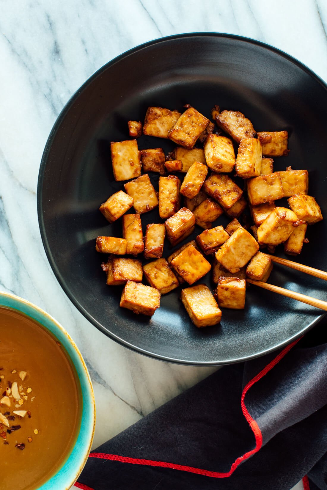 oven baked tofu in black bowl with chop sticks
