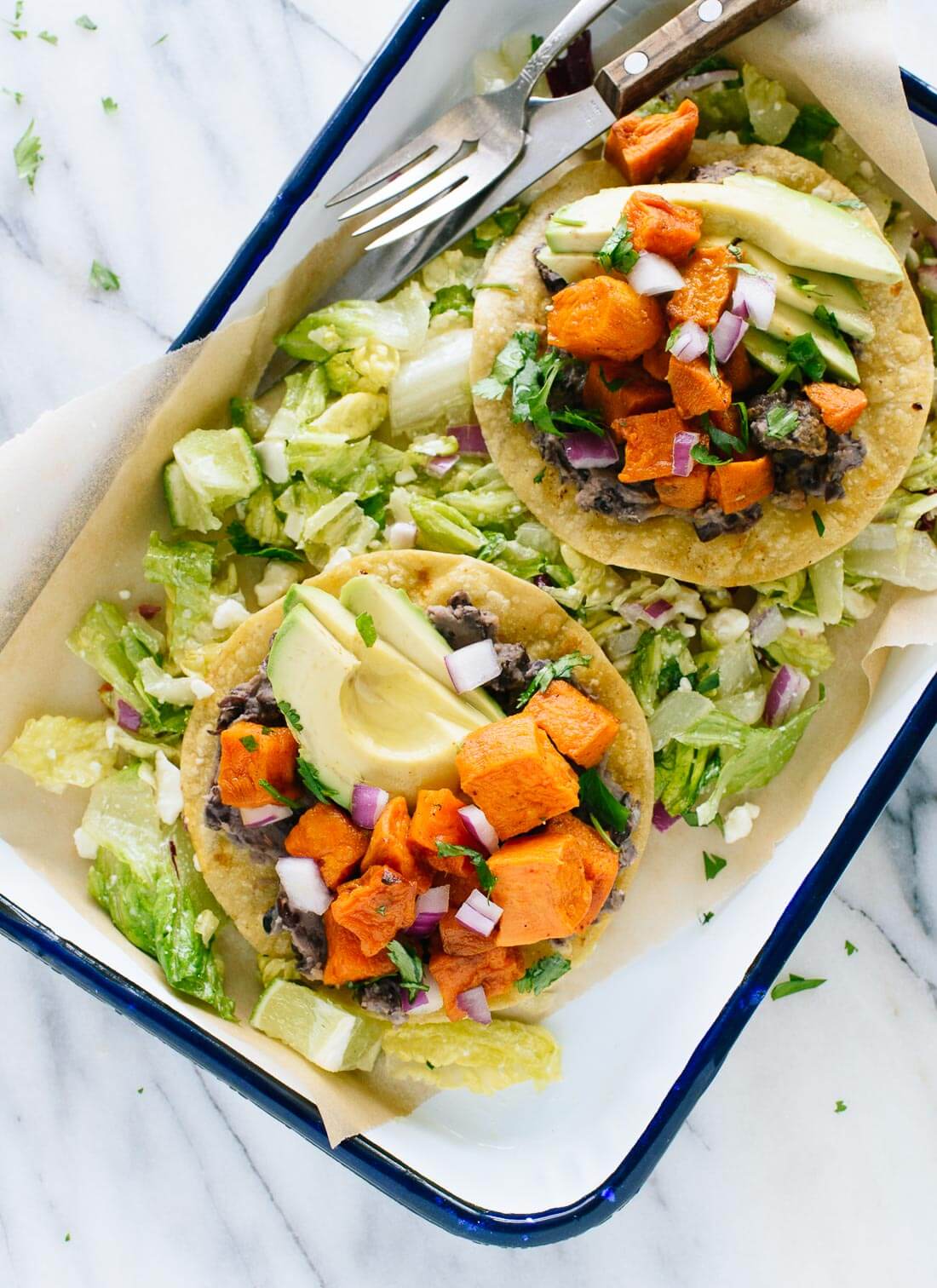 This vegetarian tostadas recipe features roasted sweet potatoes and healthy "refried" black beans, served on a crisp salad. Gluten free and easily vegan!