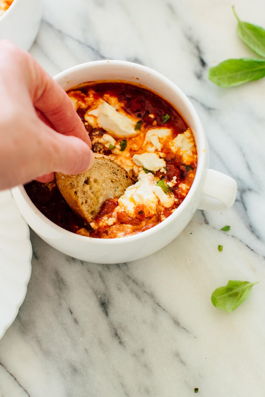 bread dipped into baked tomato and goat cheese dip