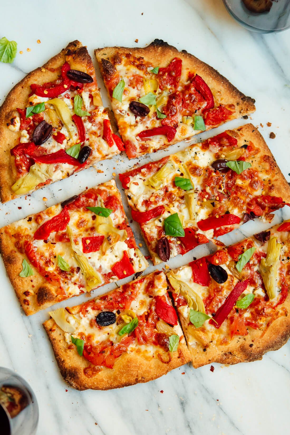 Greek pizza recipe, featuring feta, roasted red peppers, artichoke and olives!